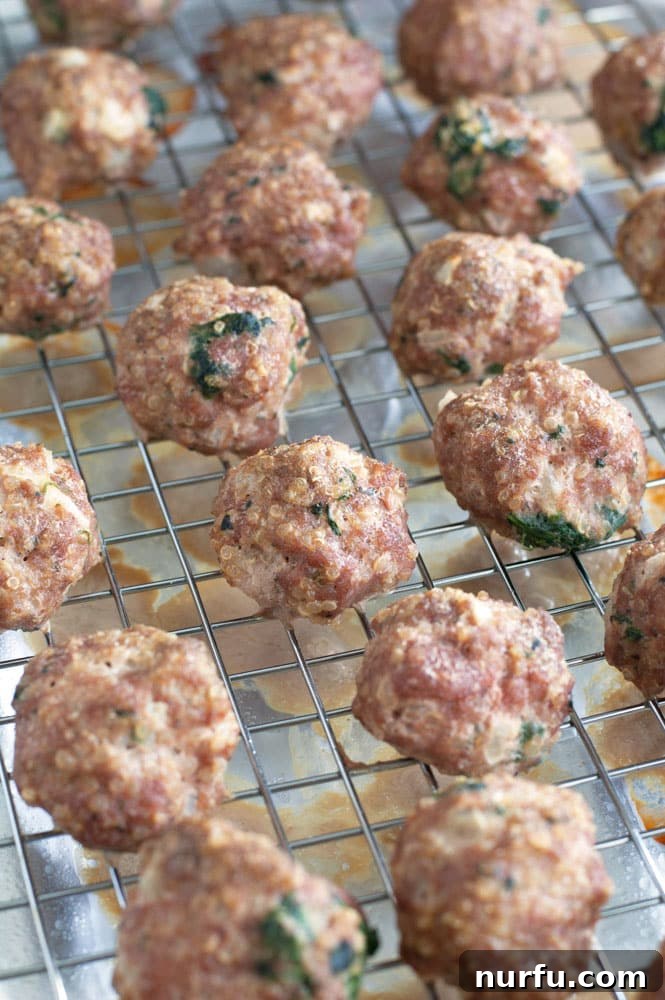 Freshly baked Turkey Quinoa Spinach Meatballs arranged on a baking pan, showing their golden brown exterior.