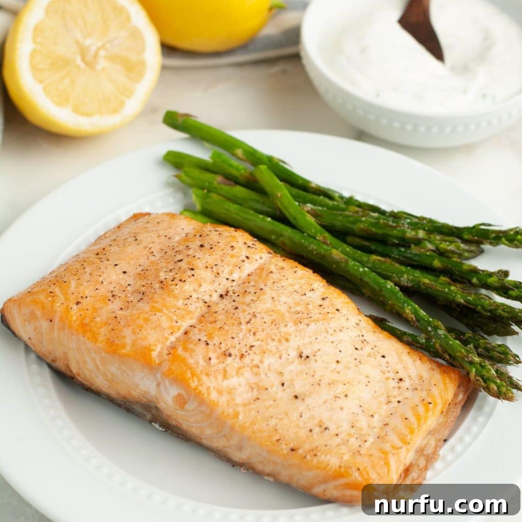 Salmon and asparagus on a plate, showcasing a perfectly cooked salmon fillet.