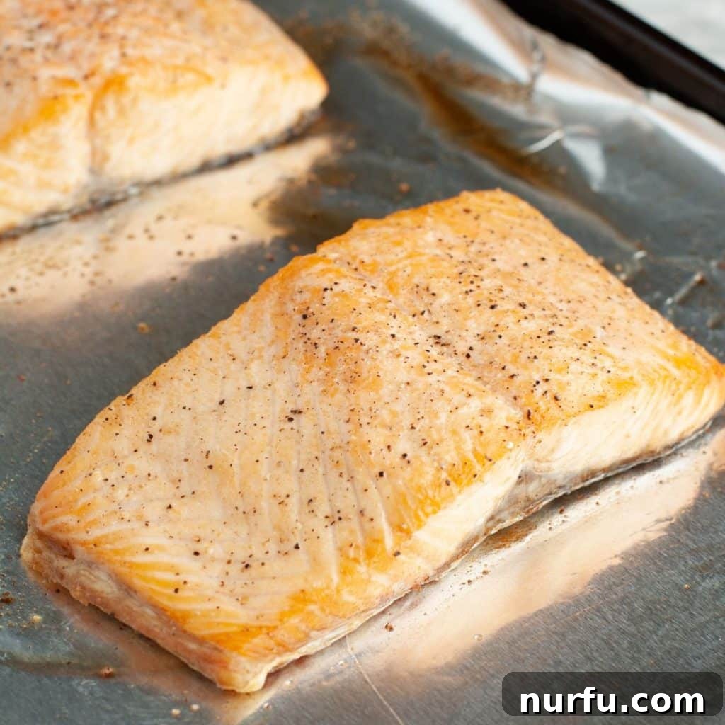 A perfectly cooked salmon fillet on foil, showing its flaky texture and golden crust.