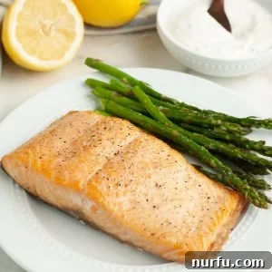 Salmon and asparagus on a plate, showcasing a perfectly cooked salmon fillet.