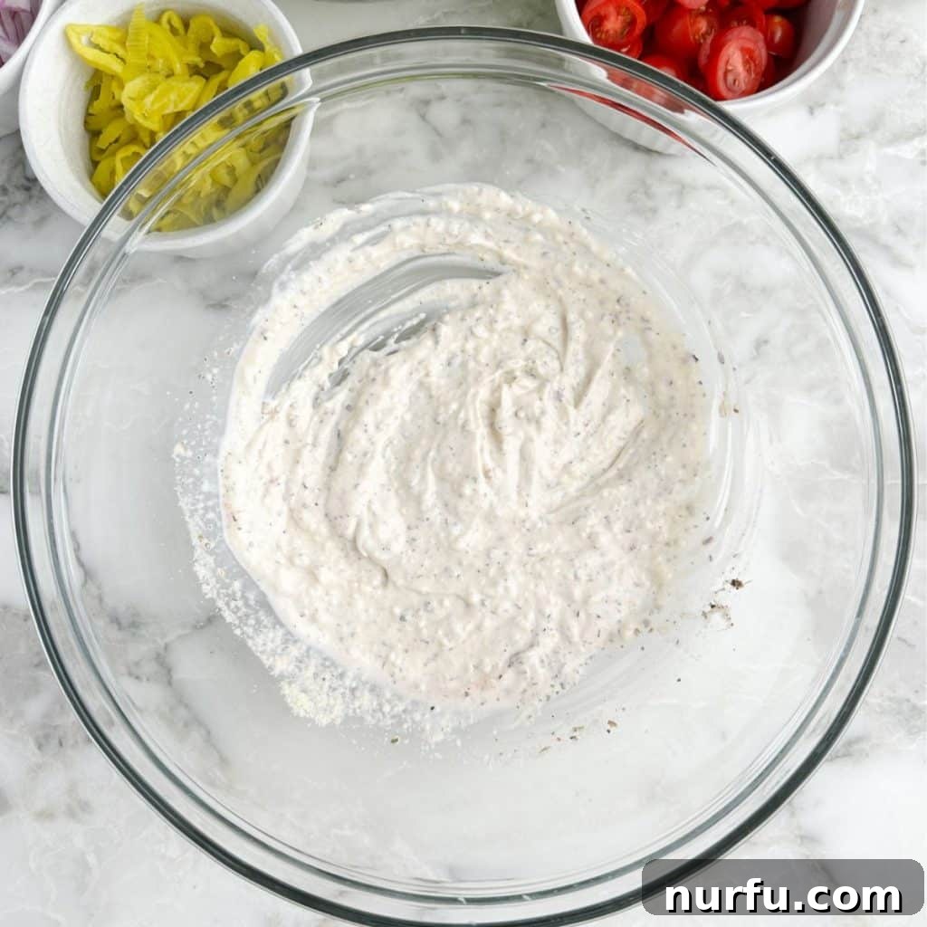 A glass bowl containing the creamy, tangy dressing for the Grinder Salad, perfectly mixed and ready for the other ingredients.