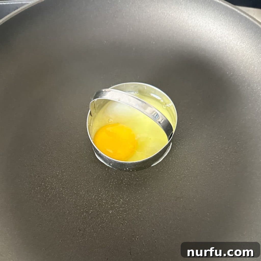The Ultimate Homemade Breakfast Sausage Muffin 5 An egg being cooked in a metal biscuit cutter within a hot skillet, replicating the round shape of a McDonald's egg.