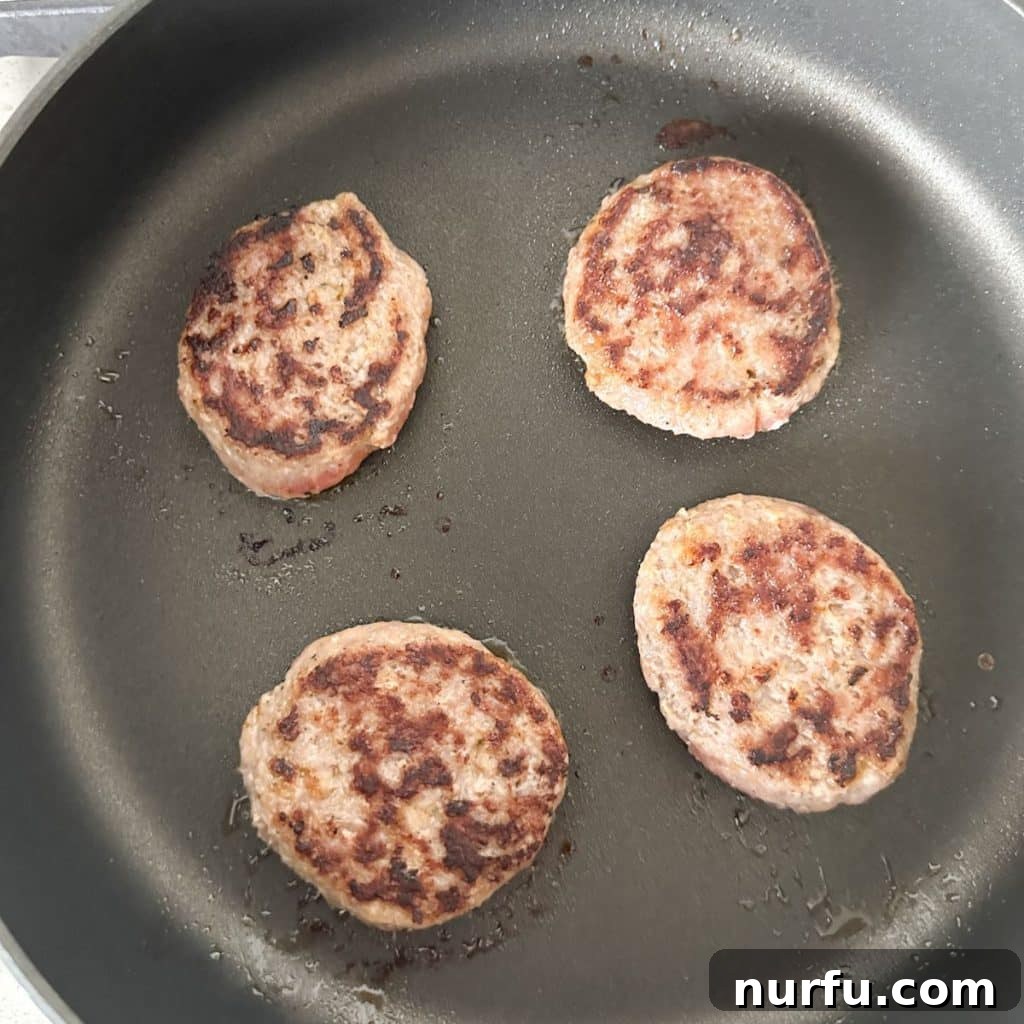 The Ultimate Homemade Breakfast Sausage Muffin 6 Breakfast sausage patties sizzling in a hot skillet, cooking to a golden brown.