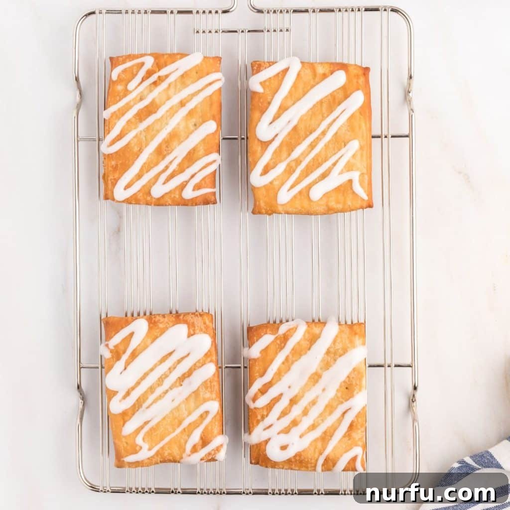Perfect Air Fryer Toaster Strudel 5 Four golden-brown toaster strudels cooling on a wire rack, ready for icing.