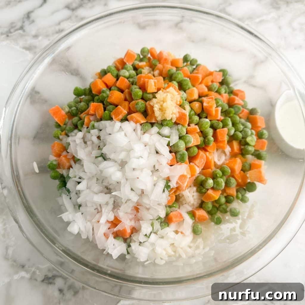 Sheet Pan Fried Rice Magic 4 A large bowl containing cooked rice, mixed peas, and carrots, ready for seasoning.
