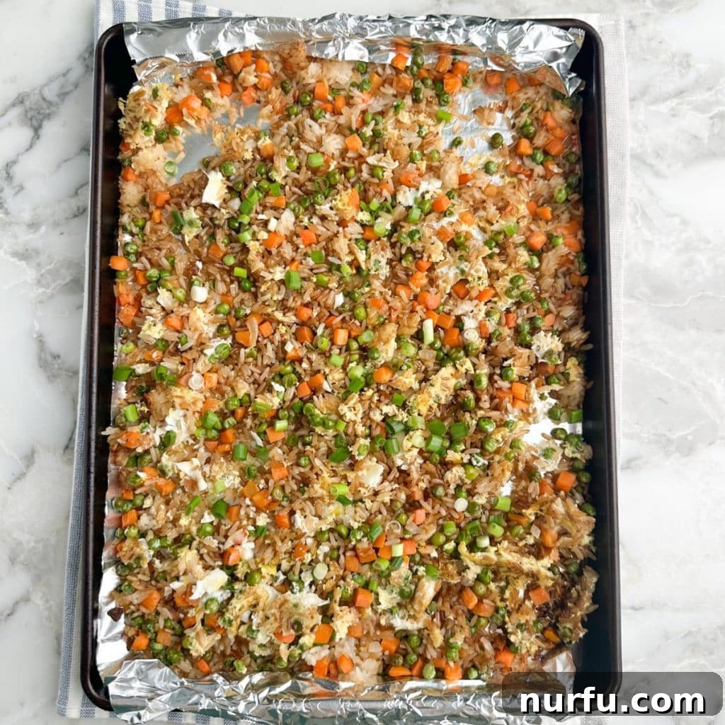 Sheet Pan Fried Rice Magic 6 Rice and vegetables spread evenly on a sheet pan, baking in the oven for a crispy texture.