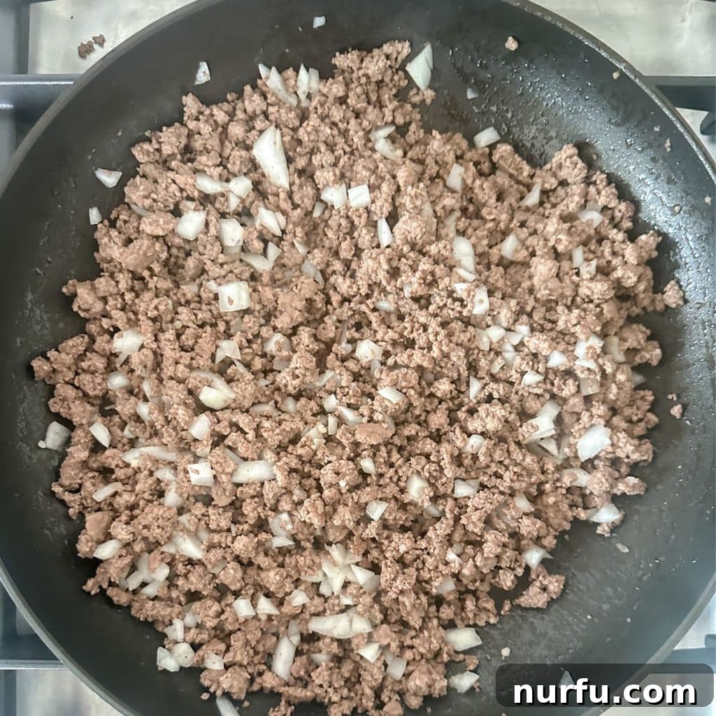 Ultimate Texas Toast Sloppy Joes 4 A large skillet containing perfectly cooked ground beef and sautéed onions, forming the savory base of the sloppy joe mixture.
