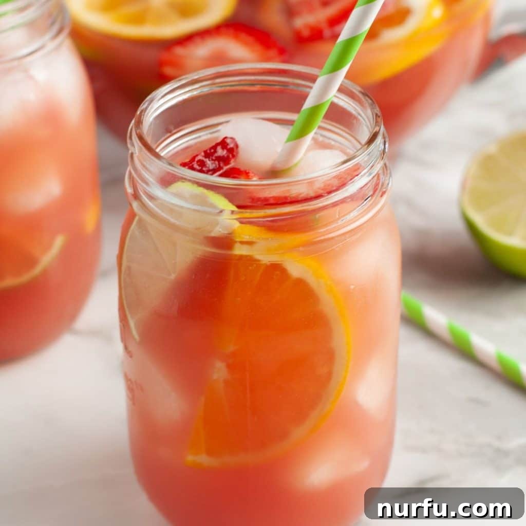 Vibrant Party Fruit Punch 2 A refreshing glass of homemade fruit punch, garnished with a slice of orange and a red cherry, with a green straw. Perfect for parties and summer gatherings.
