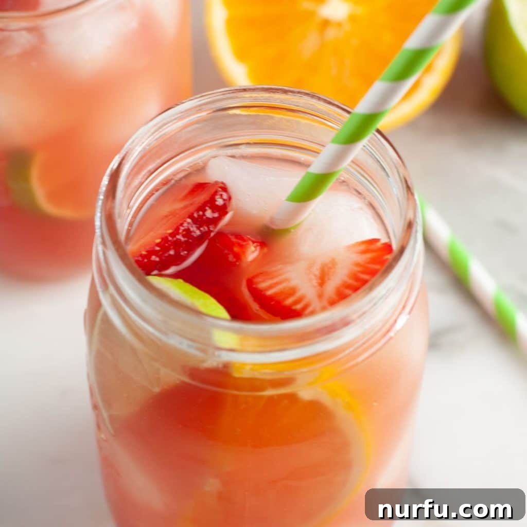 Vibrant Party Fruit Punch 4 A close-up of a glass of vibrant fruit punch with a green straw and a slice of orange garnish, ready to be enjoyed.
