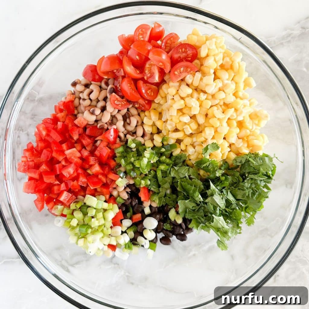 Lone Star Bean Fiesta 5 A large mixing bowl containing a vibrant, freshly prepared Texas Caviar before the dressing is added, showing a colorful blend of chopped peppers, green onion, cilantro, corn kernels, and two types of beans, all ready for the final step.