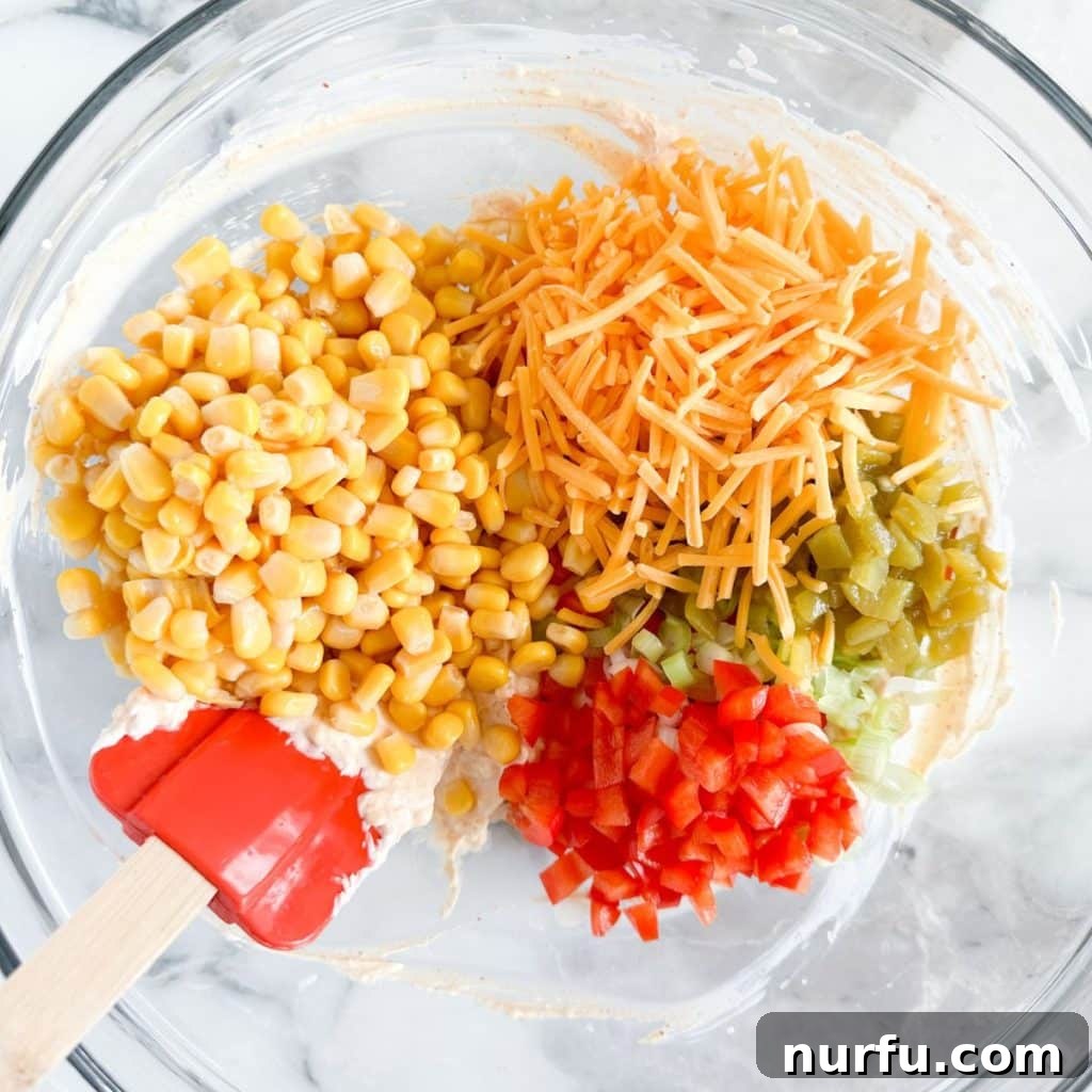 Velvety Cream Cheese Corn Dip 5 Bowl with shredded cheese, corn, diced red pepper, and green chilies mixed into the creamy base.