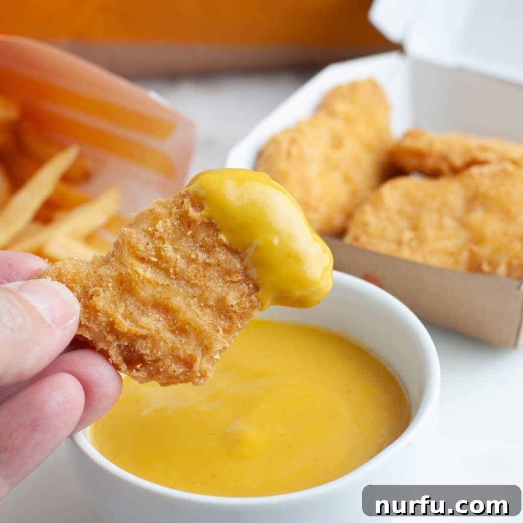 McDonald's Hot Mustard Sauce Copycat Recipe 2 Crispy chicken nugget being dipped into a bowl of homemade McDonald's hot mustard sauce.