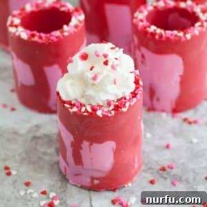 Red and pink candy shot glasses filled with whipped cream.