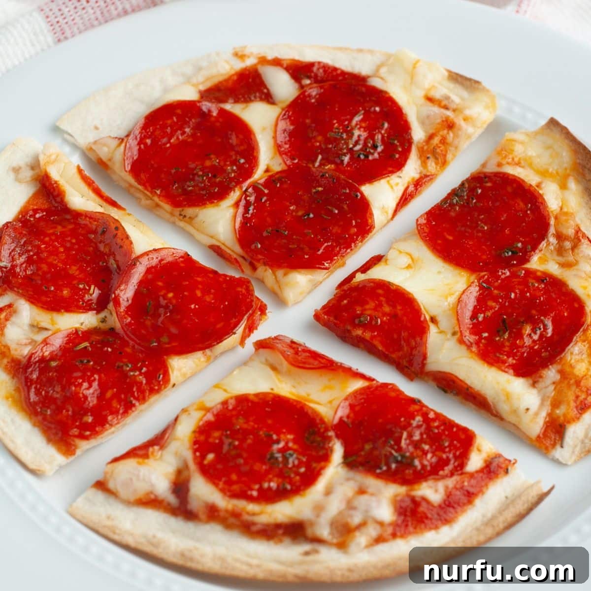 Effortless Tortilla Pizza 6 A freshly baked, vibrant pepperoni tortilla pizza, sliced and ready to be served, showcasing its crispy crust and perfectly melted cheese.