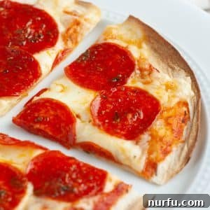 A delectable slice of crispy tortilla pizza with pepperoni and melted cheese, resting on a white plate, ready to be enjoyed.