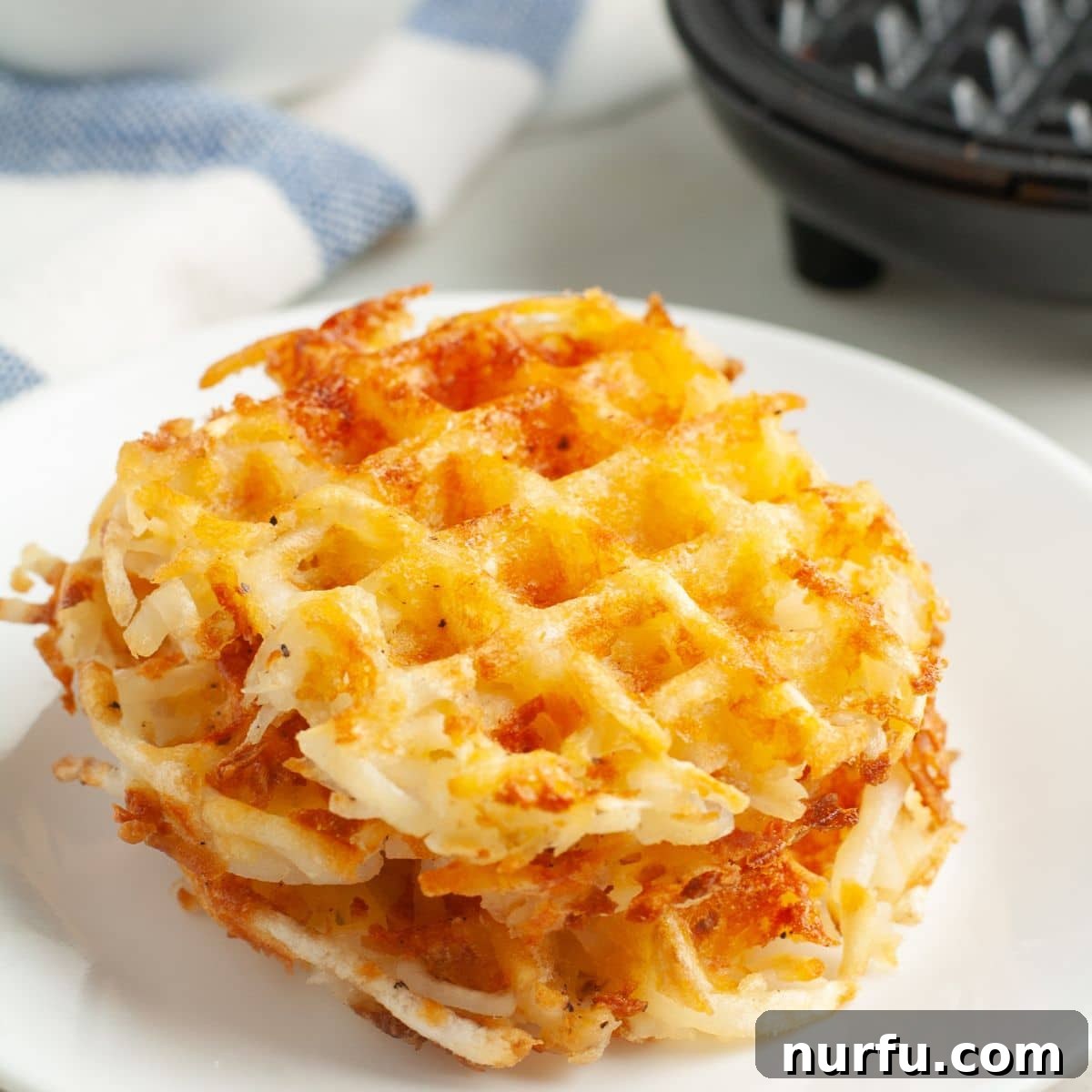 Crispy Waffle Hash Browns 7 A beautiful stack of three golden-brown hash brown waffles, showing off their crispy edges and inviting texture.