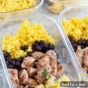Container with chicken, black beans, yellow rice and pineapple.