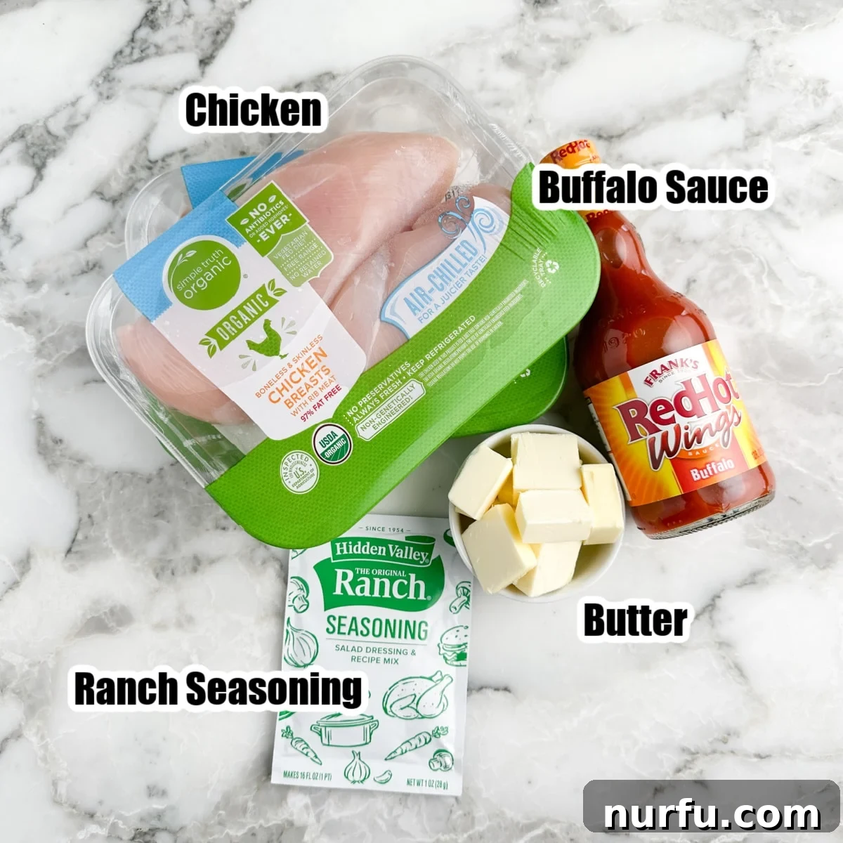Effortless Slow Cooker Buffalo Chicken 3 Pack of chicken breast, bottle of buffalo sauce, butter sticks, and a packet of ranch seasoning, laid out on a surface.