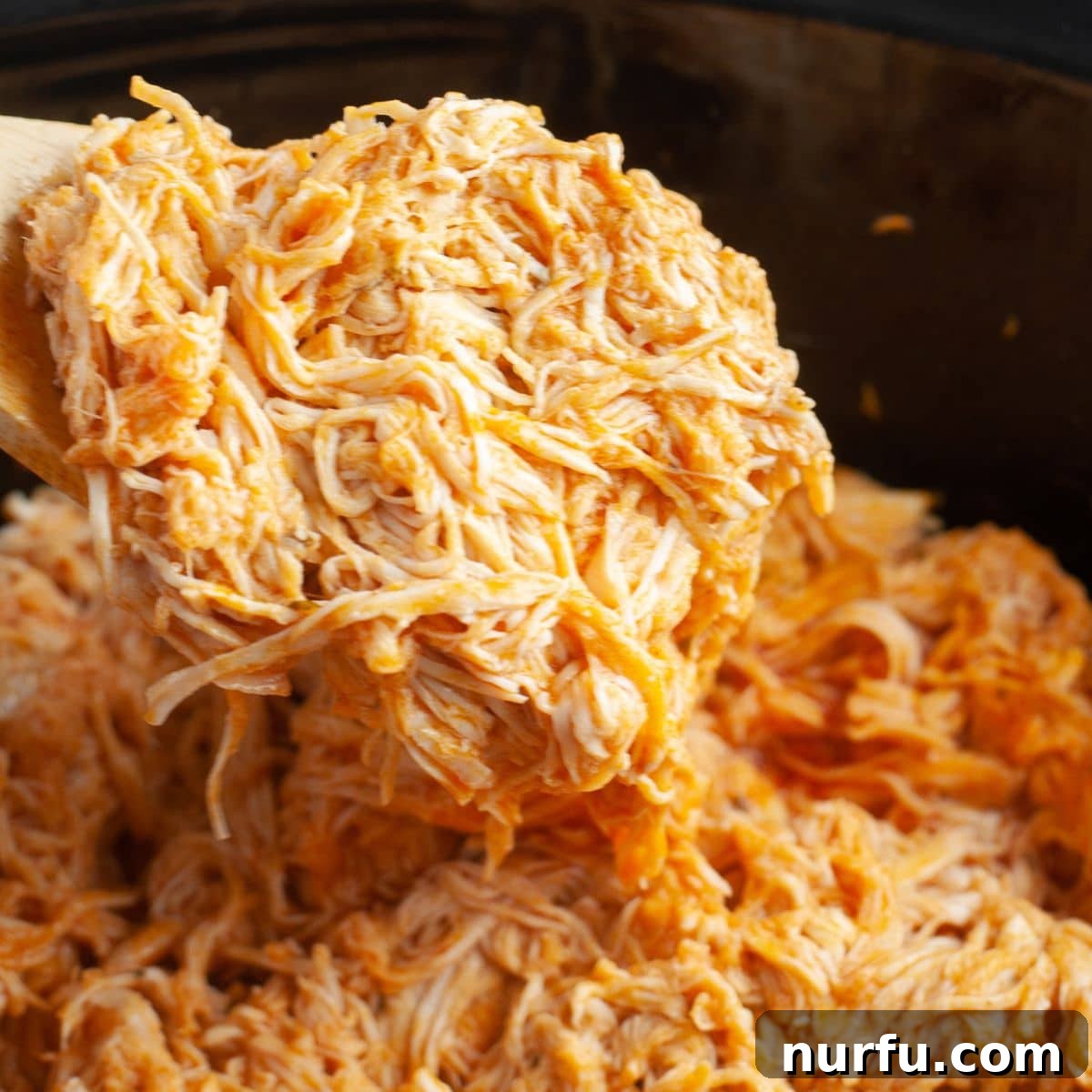 Effortless Slow Cooker Buffalo Chicken 7 Shredded buffalo chicken in a slow cooker, ready to be scooped out.