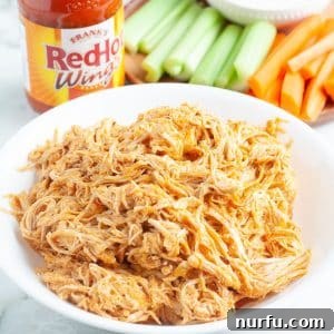 Effortless Slow Cooker Buffalo Chicken 8 Bowl of shredded chicken with hot sauce.