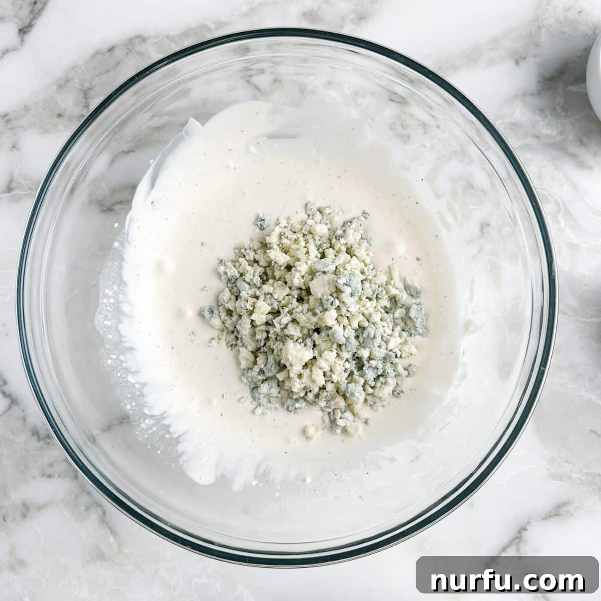 Bowl with mayonnaise dressing and blue cheese crumbles.