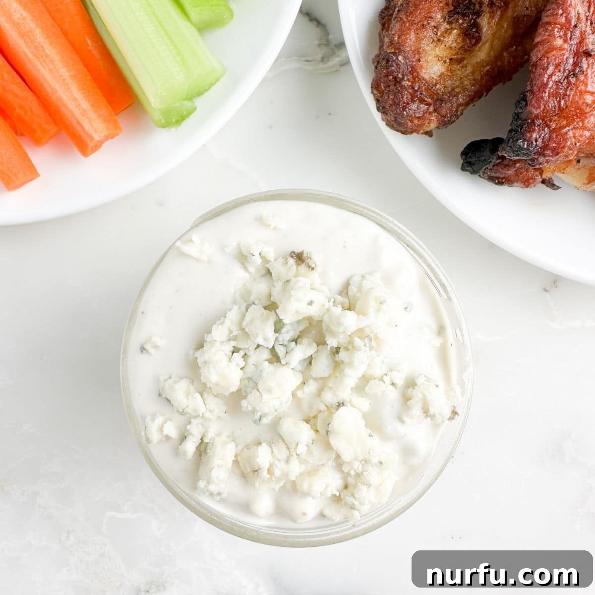 Bowl of blue cheese dressing with chicken wings.