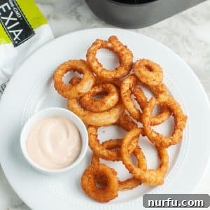 Plate of onion rings with a bowl of creamy sauce.
