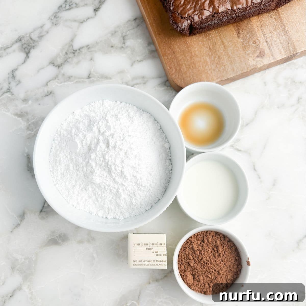 Velvety Brownie Frosting 3 Bowl of powdered sugar, vanilla, milk, cocoa powder, and butter.