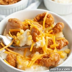 Bowl of fried chicken, mashed potatoes, and shredded cheese.