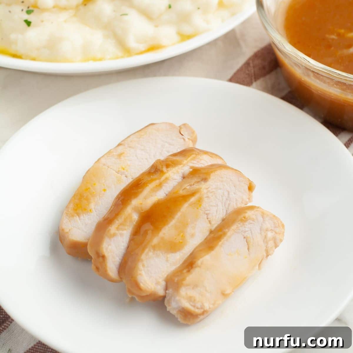 Beautifully sliced turkey tenderloin arranged on a plate, drenched in rich, savory gravy.