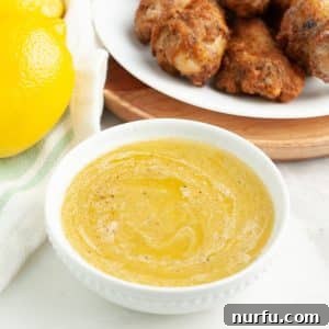 Bowl of lemon pepper sauce with a plate of chicken wings.