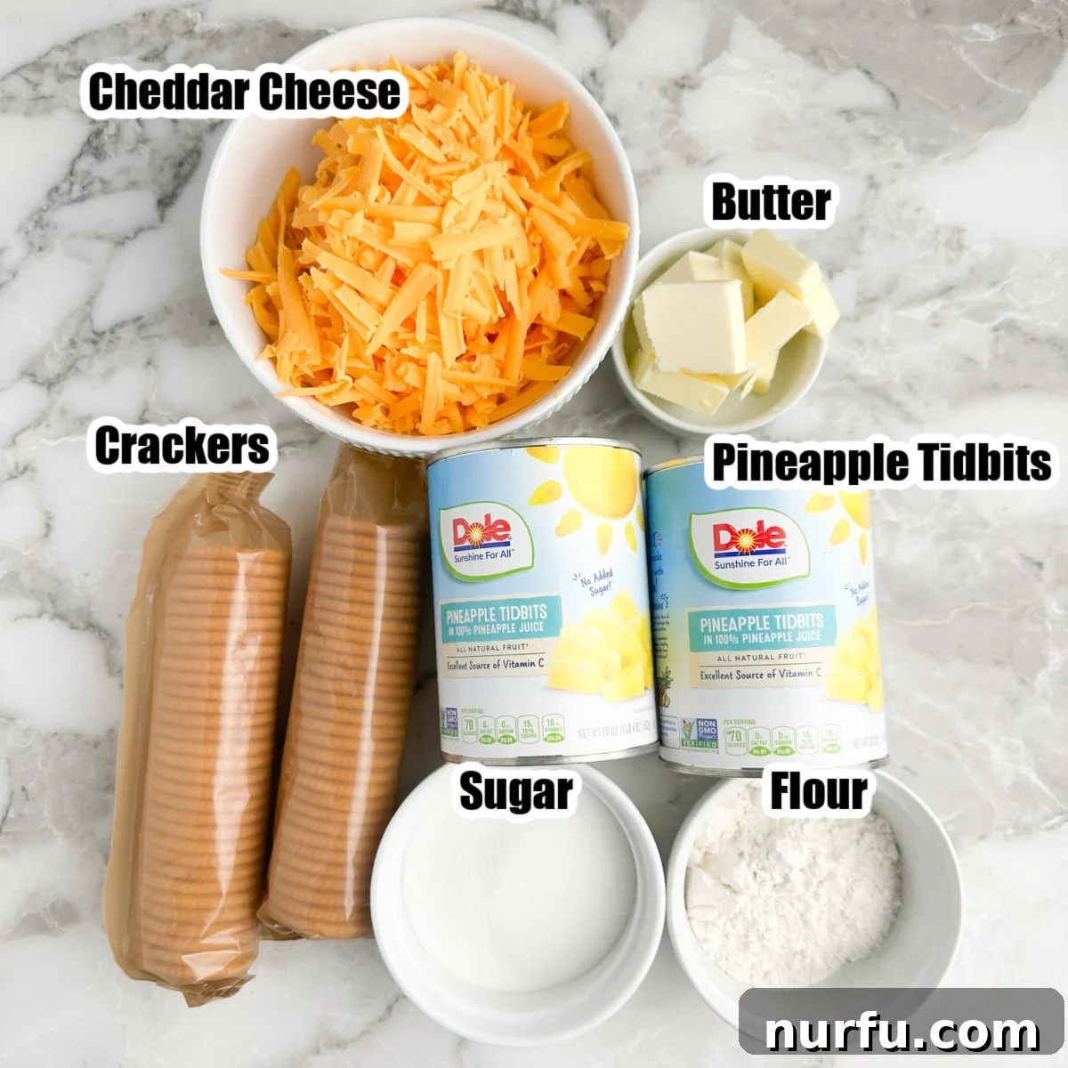Tropical Pineapple Delight 3 A perfectly arranged flat lay showcasing all the fresh ingredients needed for a delicious pineapple casserole: a bowl of vibrant shredded sharp cheddar cheese, sticks of rich unsalted butter, a bowl of granulated sugar, a pile of all-purpose flour, two cans of golden pineapple tidbits, and a sleeve of classic buttery crackers.