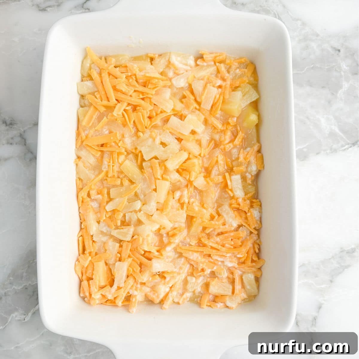 Tropical Pineapple Delight 5 A glass casserole dish elegantly filled with the prepared pineapple and cheese mixture, perfectly smooth and ready to receive its golden cracker topping.
