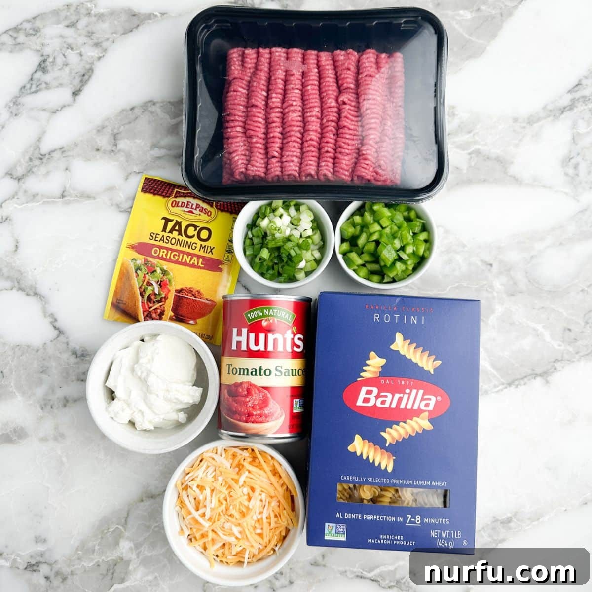 The essential ingredients laid out: Ground beef, taco seasonings, rotini pasta, sour cream, and cheese, ready for assembly into a Taco Twist Casserole.