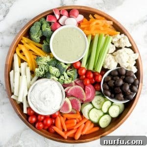 Crafting a Stunning Veggie Platter 5 A round platter generously filled with an assortment of crisp, cut vegetables and two inviting bowls of creamy ranch dip.
