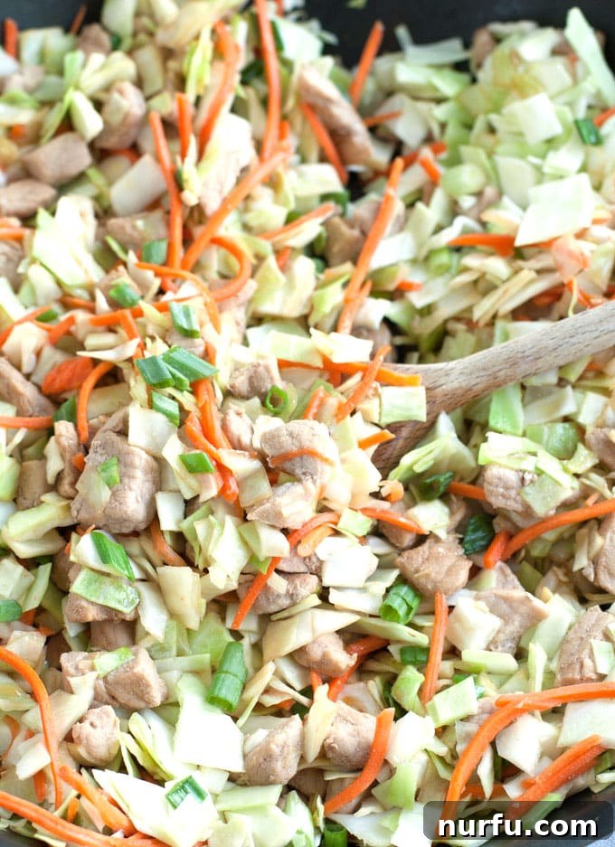 Inside-Out Pork Egg Roll Bowl 5 A serving of Pork Egg Roll in a Bowl garnished with fresh green onions and sesame seeds, ready to be enjoyed.