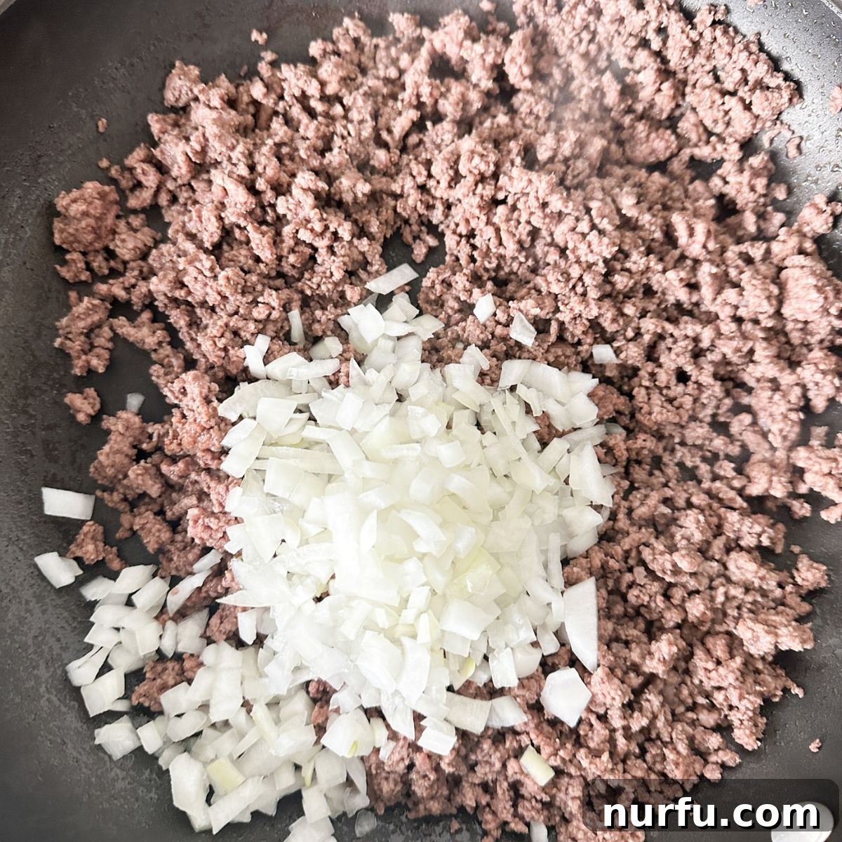 Hearty Slumgullion America's Beloved Goulash 4 Skillet containing browned ground beef and diced onion and garlic, preparing the savory base for American Goulash.