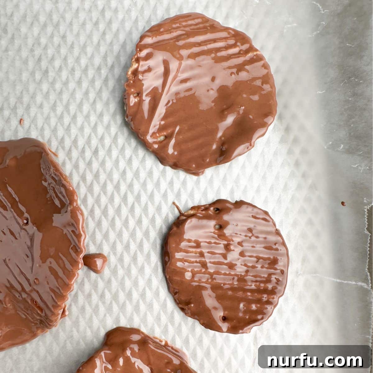 Sweet Salty Chocolate Chip Perfection 5 Freshly dipped chocolate covered potato chips laid out neatly on a parchment-lined baking sheet, cooling and setting.