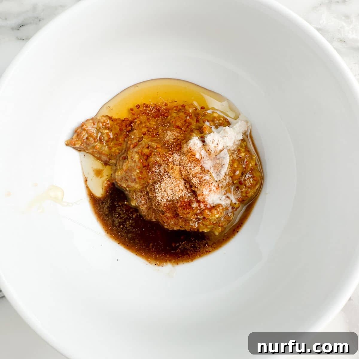 Craft Your Own Creole Mustard 4 A bowl showcasing the initial mixture of honey, stone ground mustard, and Worcestershire sauce, before other seasonings are added.