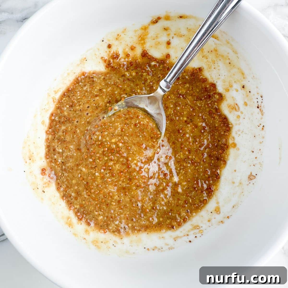 Craft Your Own Creole Mustard 5 A bowl of freshly made grainy Creole mustard with a spoon resting in it, ready for chilling.