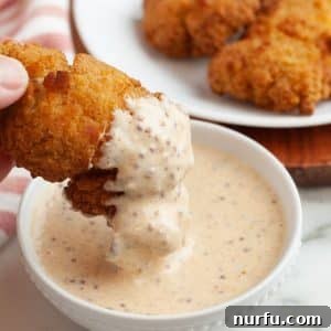 Bowl of sauce with chicken chicken dipping into the sauce.