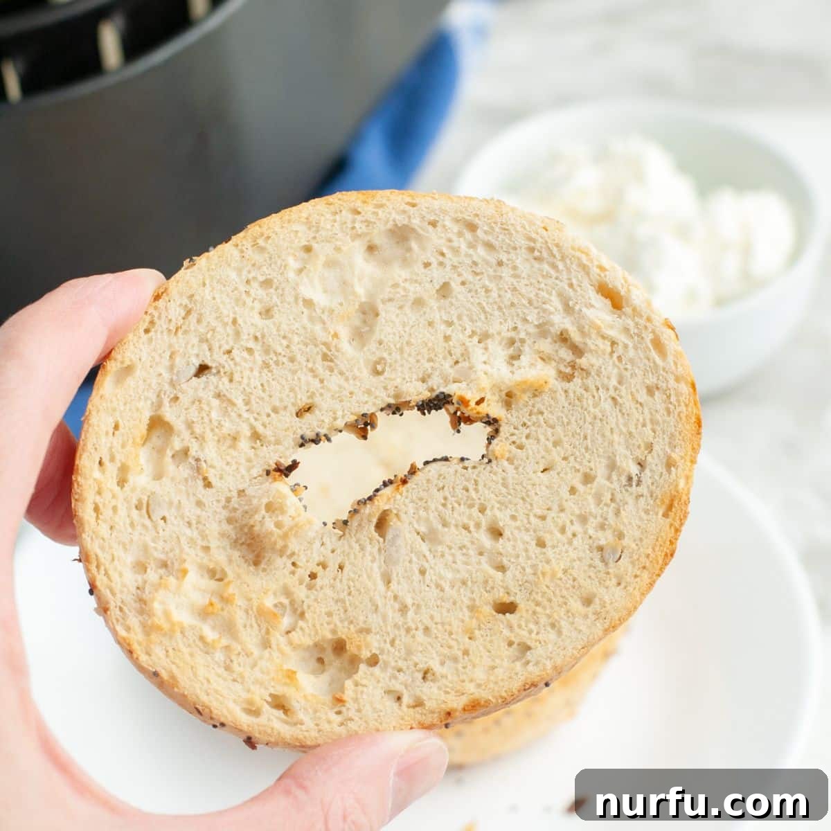 Air Fryer Bagels Crispy And Quick 4 A hand holds a perfectly toasted bagel, showcasing its crispy, golden-brown crust and inviting texture. The focus is on the delicious details of the bagel.