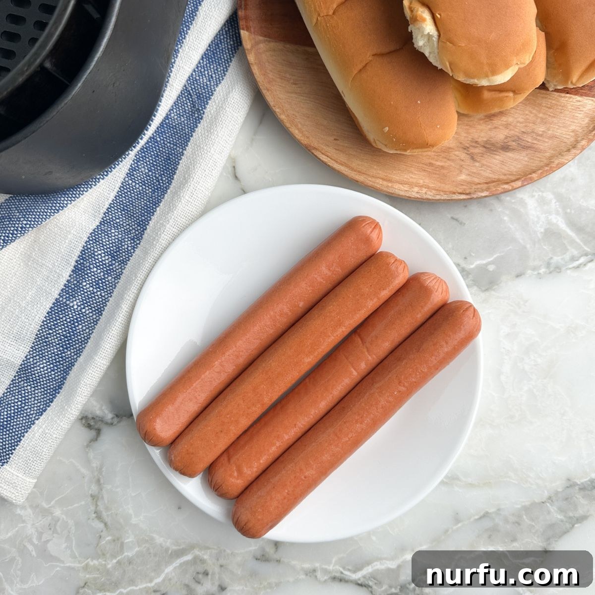 Perfect Air Fryer Hot Dogs 3 Plate of hot dogs, buns, and air fryer basket.