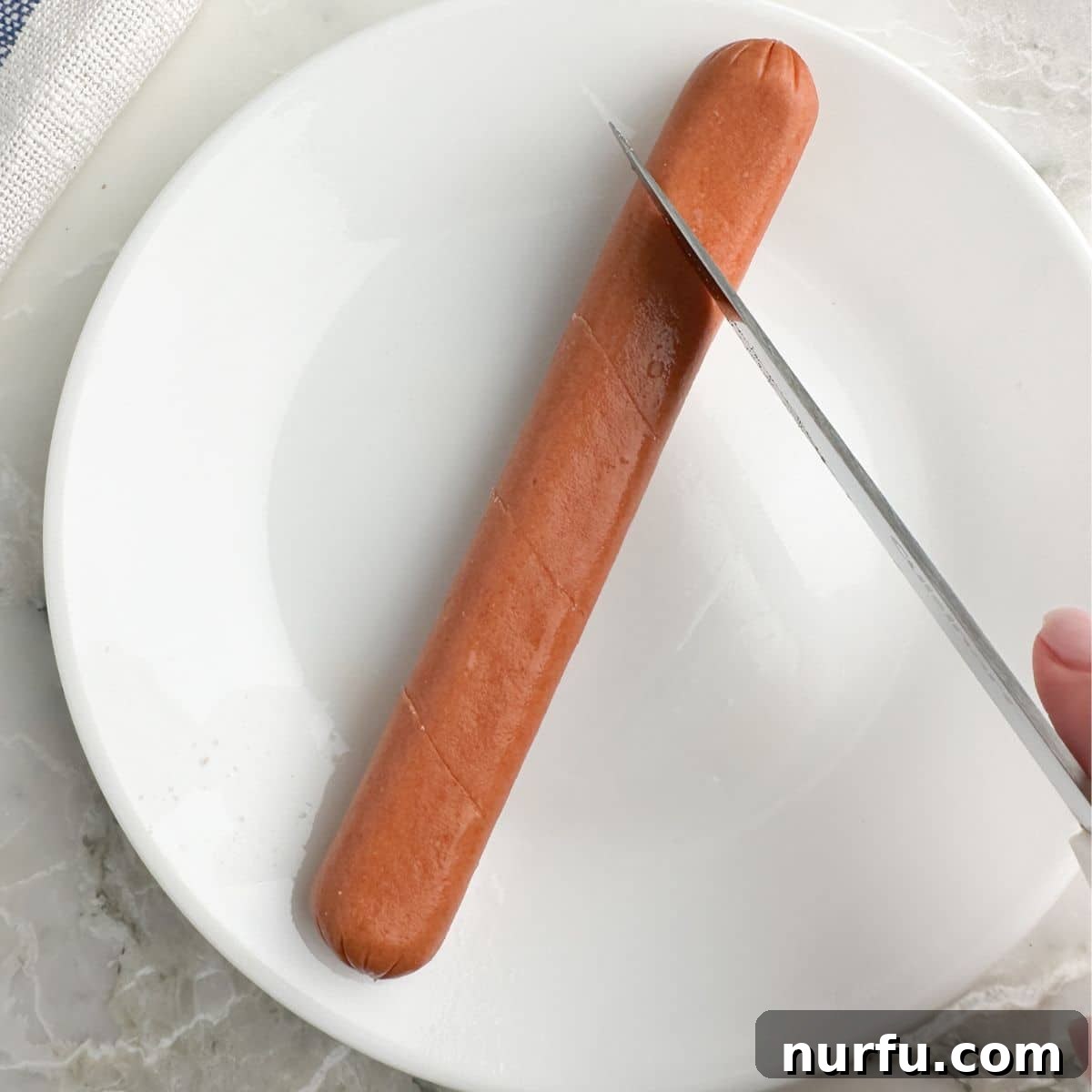 Perfect Air Fryer Hot Dogs 4 Hot dog on a plate with knife cutting into it.