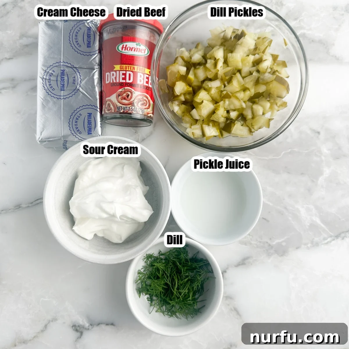 Zesty Dill Pickle & Dried Beef Dip 3 All the essential ingredients for dill pickle dip laid out: softened cream cheese, sour cream, a jar of dried beef, chopped dill pickles, a small amount of pickle juice, and fresh dill.