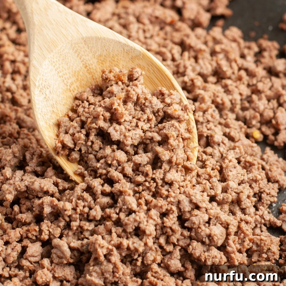 Seasoning Secrets for Ground Beef 2 Wooden spoon with perfectly seasoned cooked ground beef, showcasing its rich color and texture, ready to be served.