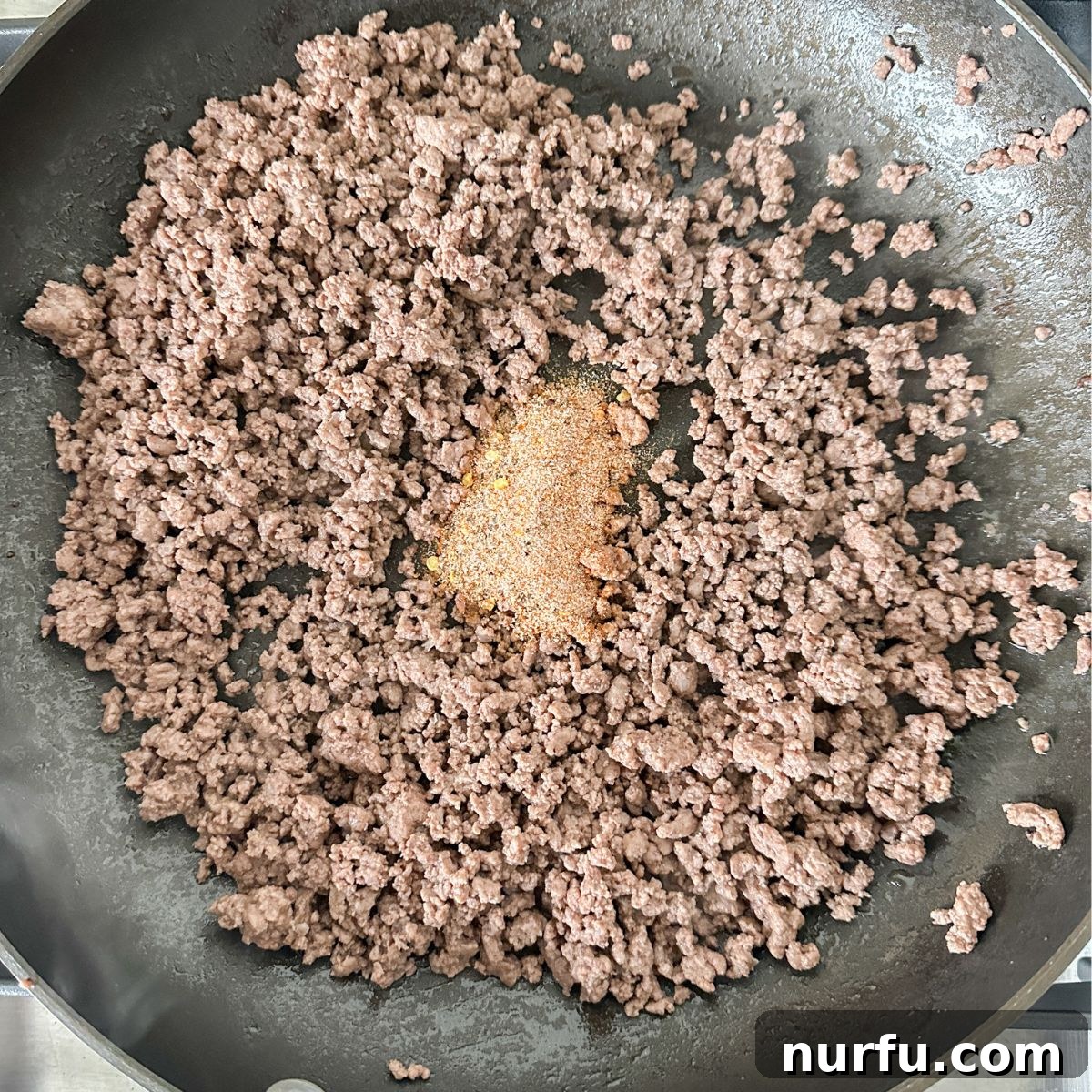Seasoning Secrets for Ground Beef 6 Cooked ground beef in a skillet, freshly drained of excess fat, with the vibrant homemade seasoning mix sprinkled generously on top, awaiting a final stir.