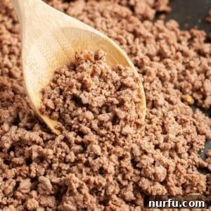 Wooden spoon with perfectly seasoned cooked ground beef, ready to be served.