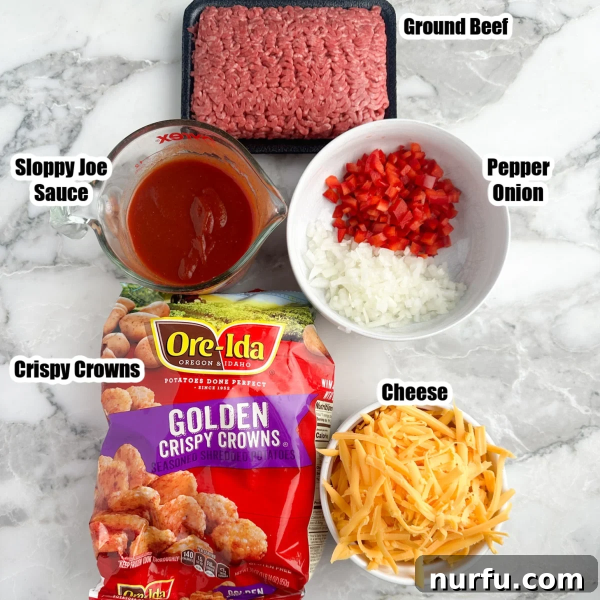 A flat lay photograph showcasing the key ingredients for Sloppy Joe Casserole: ground beef, chopped bell peppers and onions, a can of sloppy joe sauce, a bag of frozen crispy crowns, and a bowl of shredded cheddar cheese.