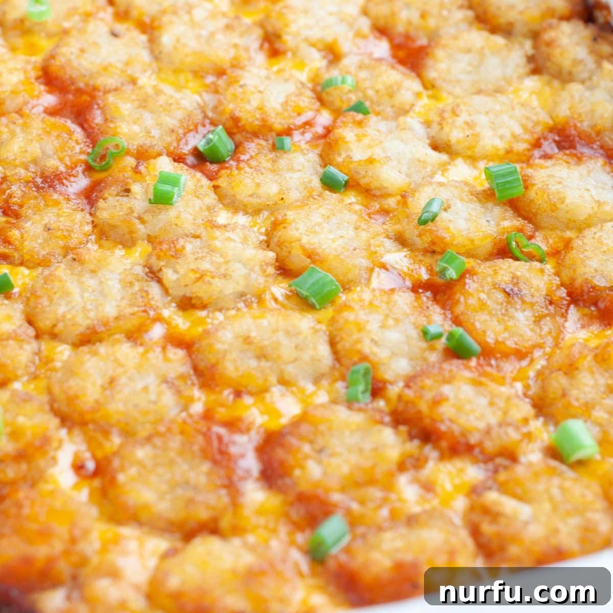 A freshly baked Sloppy Joe Tater Tot Casserole in a blue baking dish, golden brown and bubbly, ready to be served.